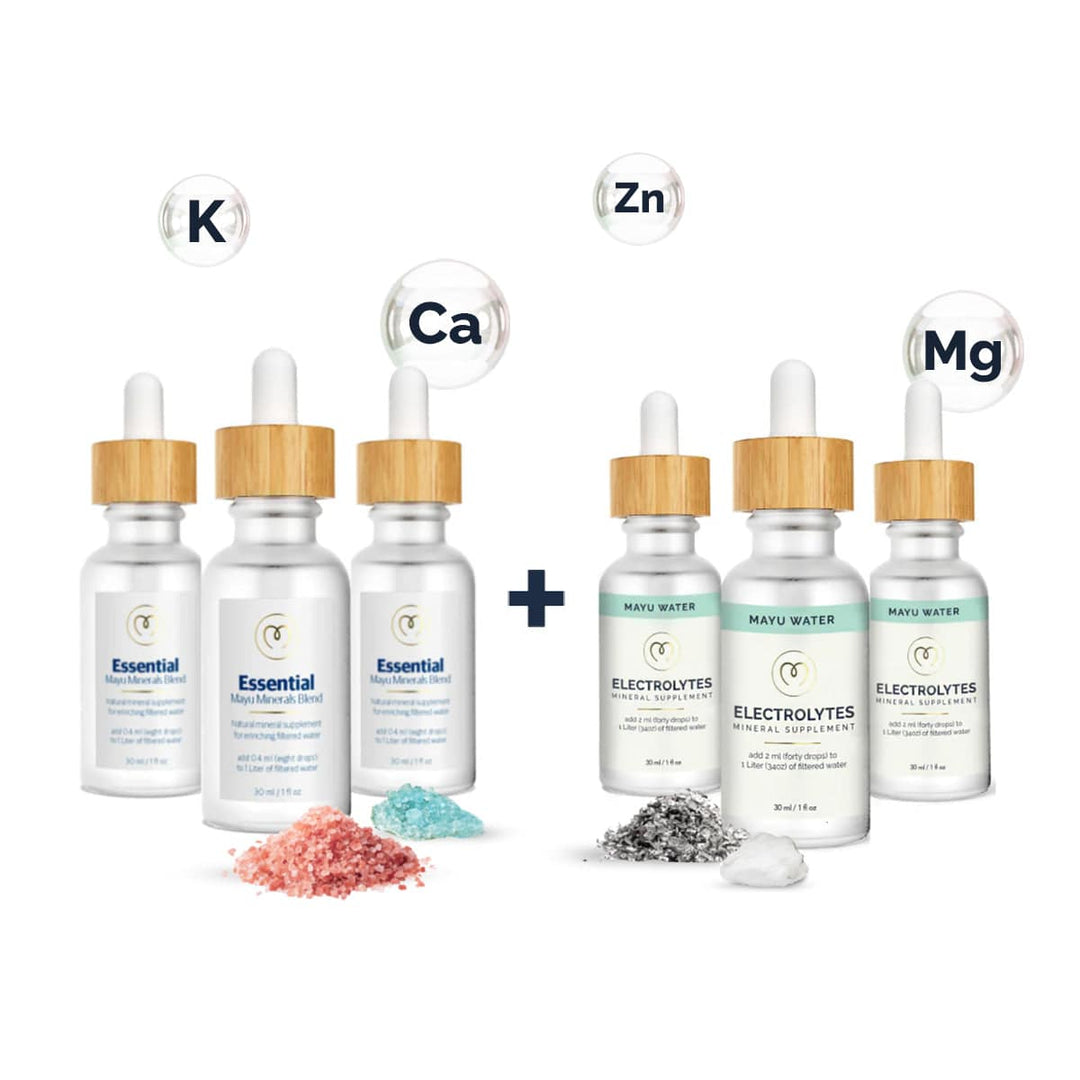 Six bamboo-capped bottles from Mayu Water’s Trace Mineral & Electrolyte Drops Stock Up Kit—three “Essential” (pink/blue salts) and three “Electrolytes” (white/gray salts)—feature K, Ca, Zn, and Mg symbols above for optimal hydration.