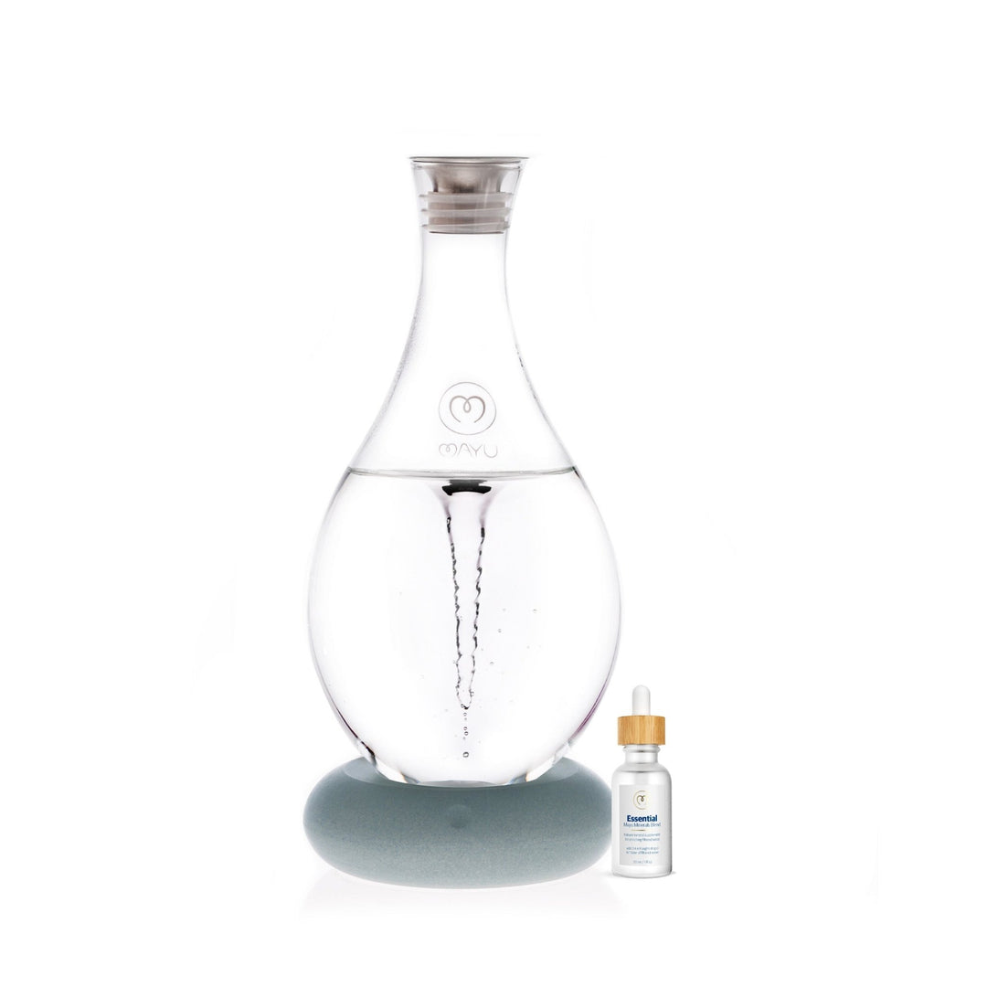 The Mayu Water Basic Starter Kit features a Swirl Structured Water Carafe with a silver lid on a round gray base, alongside an “Essential Minerals” dropper bottle, all set against a clean white background.
