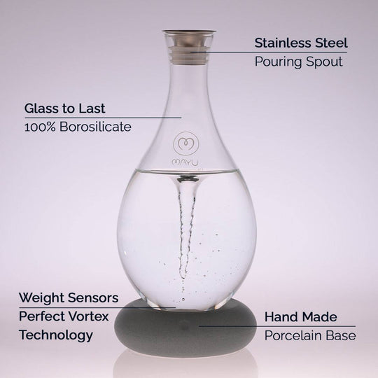 The Mayu Water Swirl Stainless Steel Pouring Spout creates a vortex in borosilicate glass, resting on a handmade porcelain base with weight sensors—modern table décor that showcases innovative vortex technology.