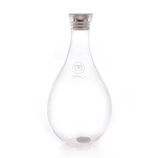 The Mayu Water Swirl Glass Carafe is a clear, teardrop-shaped borosilicate glass carafe with a silver-colored lid and a subtle heart-shaped Mayu logo on the front, shown empty against a white background.