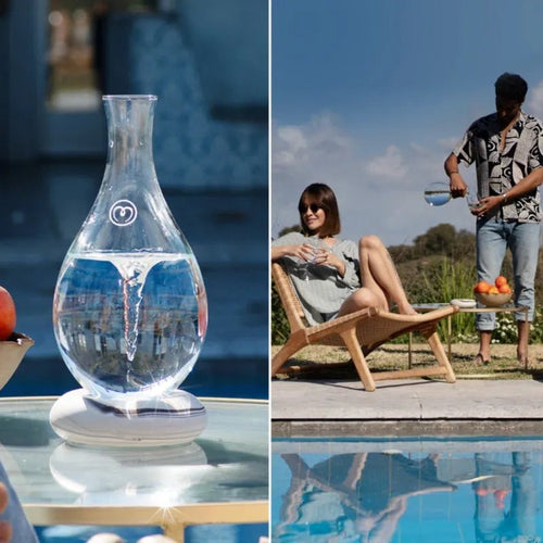 Left: The Mayu Water Swirl Structured Water Carafe, made of handblown borosilicate glass, sits on an outdoor table. Right: A man pours from the carafe for a woman by the pool; fresh fruit decorates the nearby table.