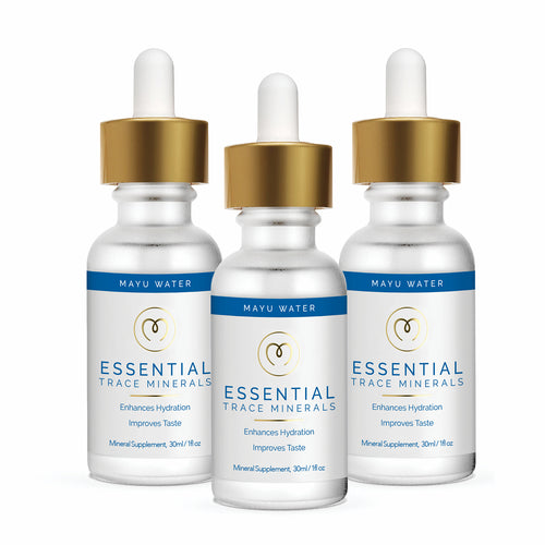 Three dropper bottles of Mayu Water Essential Minerals, featuring gold caps, white bodies, and blue accents, stand upright on a white background. The label highlights hydration, improved taste, and daily wellness through ionic minerals.