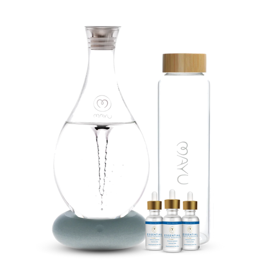 The Mayu Water Deluxe Starter Kit features a structured water carafe, a tall glass bottle with a wooden lid, and three trace mineral drop bottles, arranged on a white background to highlight optimal hydration.