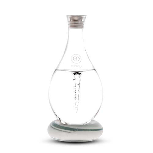 The Mayu Water Swirl Structured Water Carafe, featuring a spiral vortex design inside clear glass, sits on a round white base with a silver cap and branded logo, displayed against a plain white background.