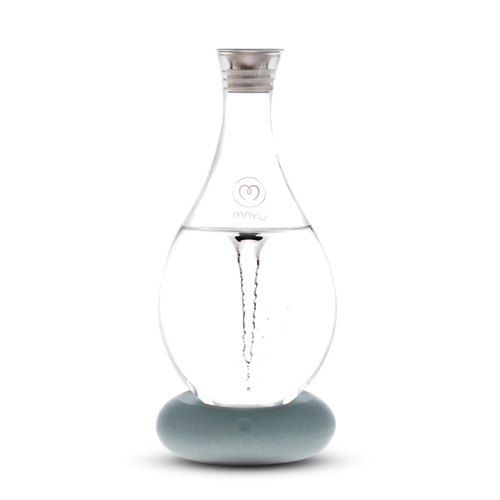 The Mayu Water Swirl Structured Water Carafe features a clear glass body with a pointed top on a round, light blue base. A visible water vortex swirls inside, all set against a white background.