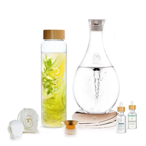 The Ultimate Wellness Bundle by Mayu Water includes a borosilicate glass bottle with herbs, a swirling carafe, wooden cap, dropper bottles, cloth pouch, round object, and small wooden dish—all displayed on a white background.