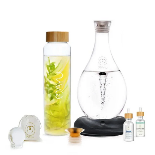 The Mayu Water Ultimate Wellness Bundle includes a structured glass bottle with bamboo lid, a swirling carafe, two droppers, drawstring pouch, small round container, and metal funnel—all shown on a white background.