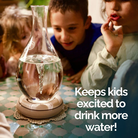 Three children watch the MAYU Swirl Carafe | Onyx by Mayu Water with swirling water on a table. Large text reads: Keeps kids excited to drink more water!.