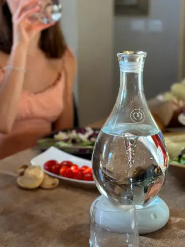 a woman sitting at a table drinking from a wine glass