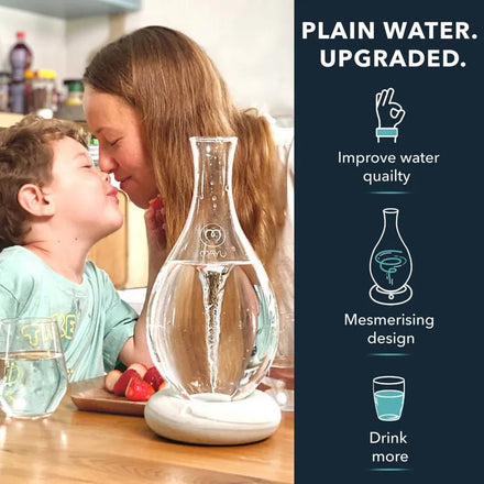 A woman and child smile and touch noses at a kitchen table with a glass and the Mayu Water Swirl Structured Water Carafe. Text: Plain water, upgraded. Enhance drinking water with mesmerising design. Drink more with Mayu Water.