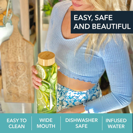 A woman in a light blue cropped sweater holds a Mayu Water Pure Glass 1.5L Bottle (Pack of 3) with a bamboo lid, filled with cucumber slices. Text: “Easy, Safe and Beautiful,” “Easy to Clean,” “Wide Mouth,” “Dishwasher Safe,” “Infused Water.”.